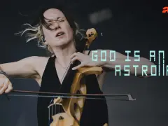 Une violoncelliste passionnée, cheveux au vent, joue avec intensité. Le texte "GOD IS AN ASTRONAUT" flotte, comme une vision cosmique.
