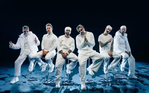 Six hommes en tenue blanche, assis sur des tabourets, évoquant l'univers des albums de Electric Callboy.