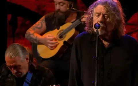 Robert Plant, le légendaire chanteur de Led Zeppelin, en pleine performance, accompagné de musiciens jouant de la guitare.