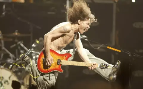Un guitariste en plein saut, cheveux au vent, déchaîne sa guitare. Un vrai héros de la guitare en pleine action.