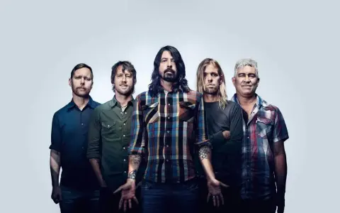 Les cinq membres du groupe Foo Fighters posent ensemble, prêts à faire vibrer le public avec leur musique.