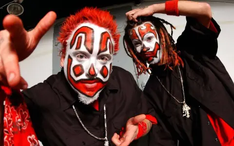 Deux membres du groupe Insane Clown Posse, visage peint en clown, cheveux rouges et dreadlocks, portent des chemises noires et des bandanas rouges.