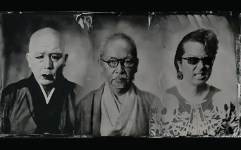 Trois portraits en noir et blanc de visages japonais. Le premier, chauve, porte une tenue sombre. Le second, avec des lunettes rondes, a une moustache. Le troisième, avec des lunettes de soleil, arbore un motif de crâne, évoquant un style metal japonais.