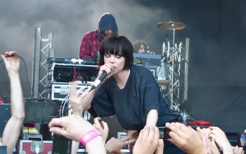 La chanteuse de Crystal Castles, Alice Glass, chante devant une foule. Un autre membre est derrière elle.