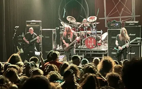 Concert de metal, musiciens sur scène, foule en délire. Le groupe semble prêt à envoyer du lourd, un vrai voyage ad patres pour les fans.