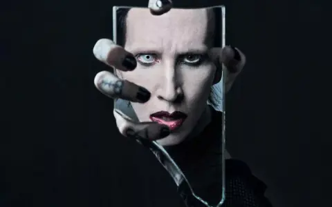 Marilyn Manson, visage décomposé dans un miroir brisé, évoquant l'esthétique sombre de ses albums.