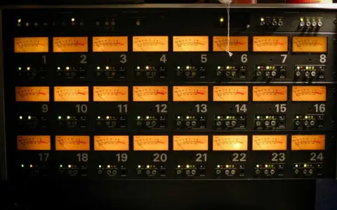 Rack d'équipements audio avec 24 vu-mètres orange illuminés, indiquant des niveaux sonores pouvant atteindre 76 décibels équivalents.