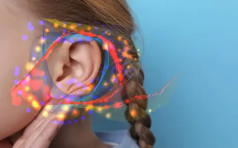 Une oreille capte des ondes sonores colorées, suggérant un seuil de douleur db.