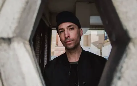 Tim Hecker, artiste sonore, regarde à travers une structure architecturale.