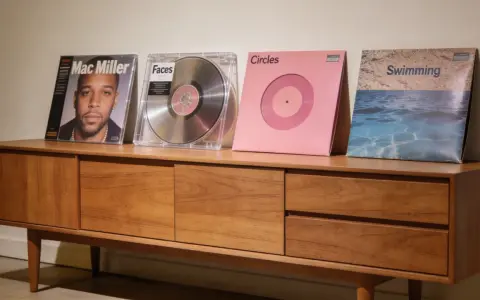Collection de vinyles de Mac Miller : "Mac Miller", "Faces", "Circles" et "Swimming" sur un meuble en bois.