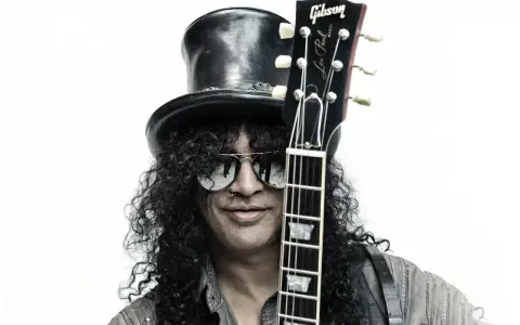 Le guitariste Slash, avec son chapeau haut-de-forme et ses lunettes de soleil, pose avec sa guitare Gibson Les Paul.