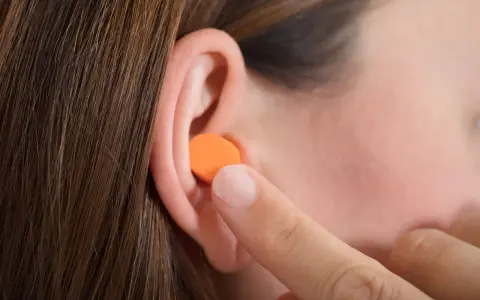Une personne insère une boule quies en mousse orange dans son oreille. Peut on laver des boules quies en mousse ?