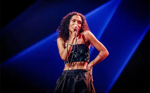 La chanteuse soul française, avec sa voix envoûtante, captive le public sous les projecteurs bleus.