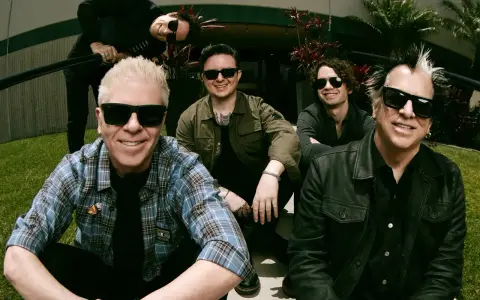Les membres de The Offspring posent ensemble, souriants et portant des lunettes de soleil. Le groupe semble prêt pour une nouvelle aventure musicale.