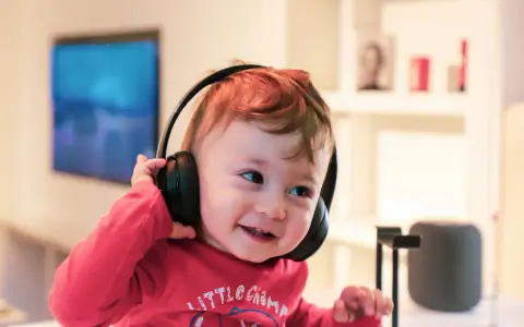 Un enfant qui ne supporte pas le bruit trouve le calme avec ses écouteurs, un sourire aux lèvres.