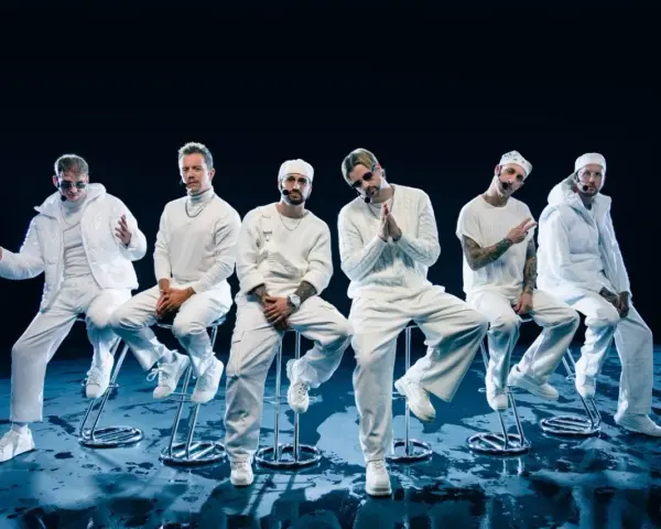 Six hommes en tenue blanche, assis sur des tabourets, évoquant l'univers des albums de Electric Callboy.