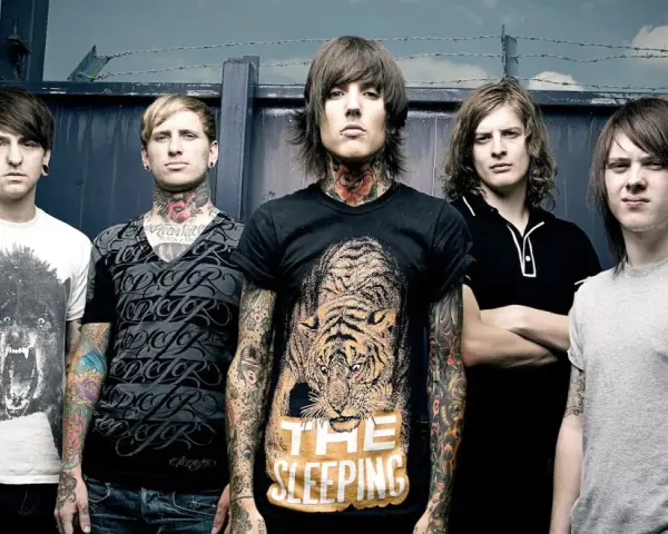 Cinq membres du groupe Bring Me The Horizon posent devant une clôture. Le chanteur porte un t-shirt avec un tigre et le texte "The Sleeping".