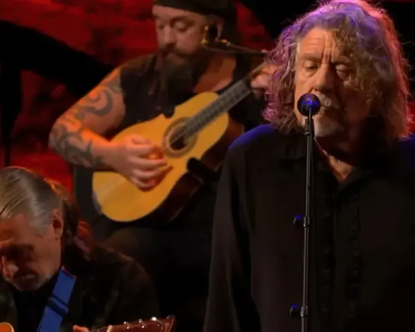 Robert Plant, le légendaire chanteur de Led Zeppelin, en pleine performance, accompagné de musiciens jouant de la guitare.