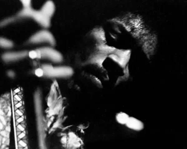 Gros plan en noir et blanc de Jimi Hendrix jouant de la guitare, évoquant l'esprit de ses albums légendaires.