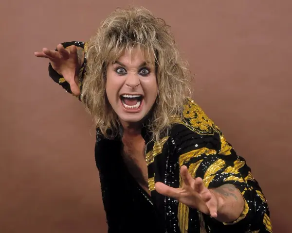Ozzy Osbourne, le prince des ténèbres, avec sa chevelure blonde ébouriffée et un regard intense, porte une veste noire ornée de motifs dorés.
