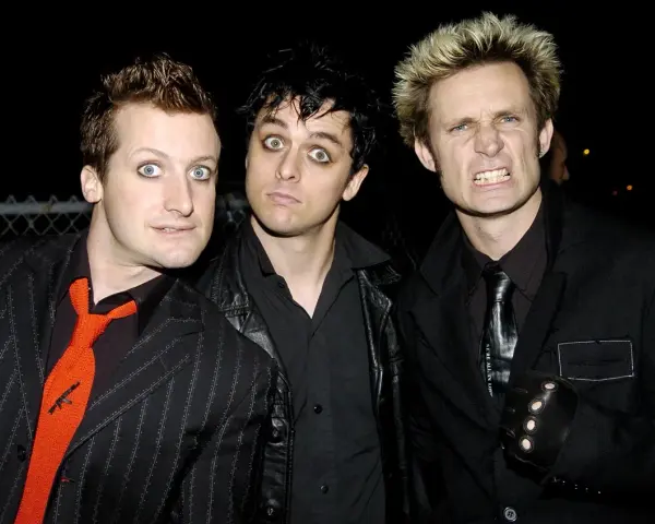 Les membres de Green Day, Billie Joe Armstrong, Mike Dirnt et Tré Cool, posent ensemble. Armstrong a les yeux écarquillés, Dirnt a un regard intense et Cool fait une grimace.