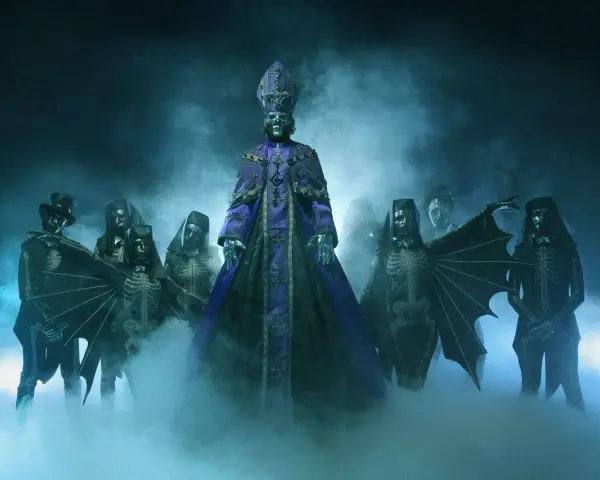Les membres de Ghost (groupe) apparaissent dans une brume bleutée, le leader en robe violette imposante, entouré de squelettes masqués et d'une silhouette à chapeau.