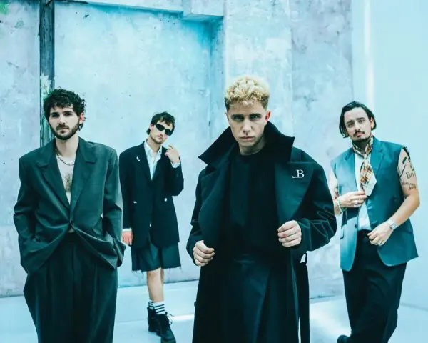 Le groupe Last Train pose devant un mur bleu clair, quatre hommes aux styles audacieux.