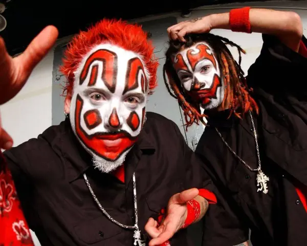 Deux membres du groupe Insane Clown Posse, visage peint en clown, cheveux rouges et dreadlocks, portent des chemises noires et des bandanas rouges.