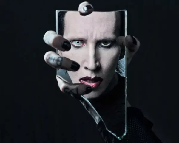 Marilyn Manson, visage décomposé dans un miroir brisé, évoquant l'esthétique sombre de ses albums.