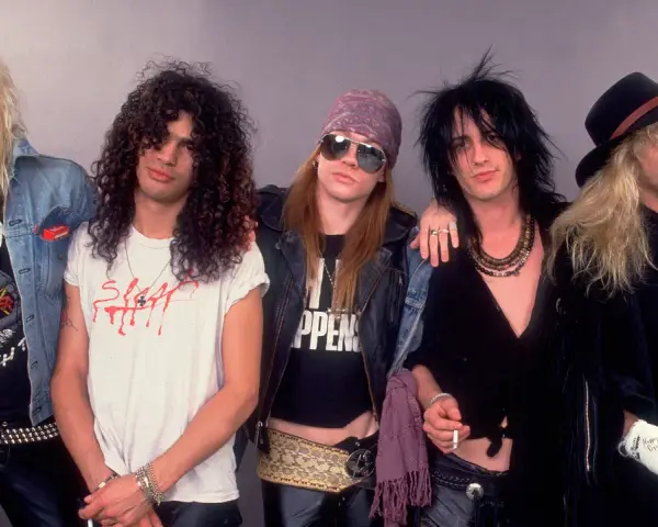 Cinq membres d'un groupe rock anglais des années 80 posent ensemble, arborant des coiffures et des tenues emblématiques de l'époque.