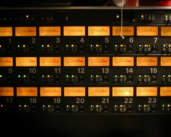 Rack d'équipements audio avec 24 vu-mètres orange illuminés, indiquant des niveaux sonores pouvant atteindre 76 décibels équivalents.