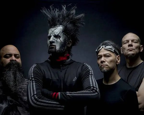 Quatre hommes, dont un avec un maquillage facial blanc et une crête, posent pour une photo. Le groupe Static X semble prêt à monter sur scène.