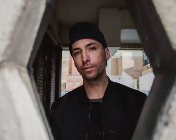 Tim Hecker, artiste sonore, regarde à travers une structure architecturale.