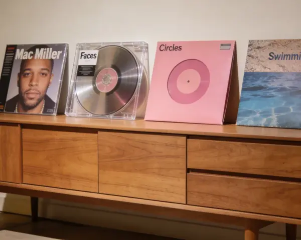 Collection de vinyles de Mac Miller : "Mac Miller", "Faces", "Circles" et "Swimming" sur un meuble en bois.