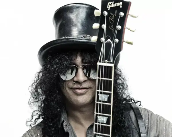 Le guitariste Slash, avec son chapeau haut-de-forme et ses lunettes de soleil, pose avec sa guitare Gibson Les Paul.