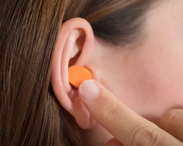 Une personne insère une boule quies en mousse orange dans son oreille. Peut on laver des boules quies en mousse ?