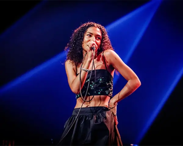 La chanteuse soul française, avec sa voix envoûtante, captive le public sous les projecteurs bleus.