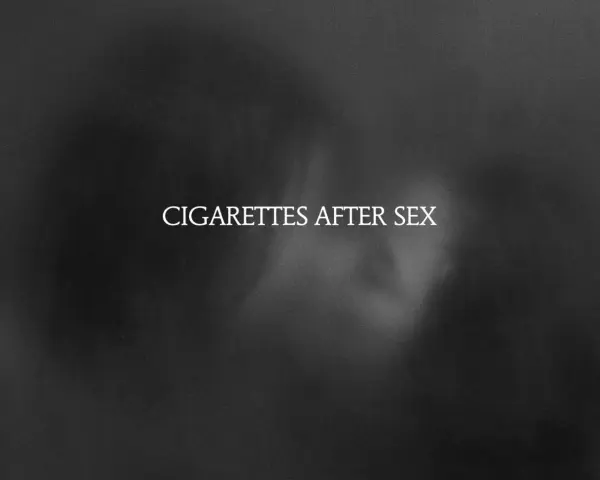 Texte blanc "CIGARETTES AFTER SEX" sur fond sombre et flou, évoquant une ambiance intime et mélancolique.