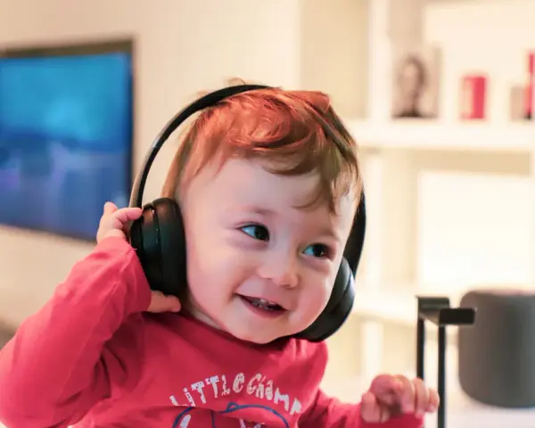 Un enfant qui ne supporte pas le bruit trouve le calme avec ses écouteurs, un sourire aux lèvres.
