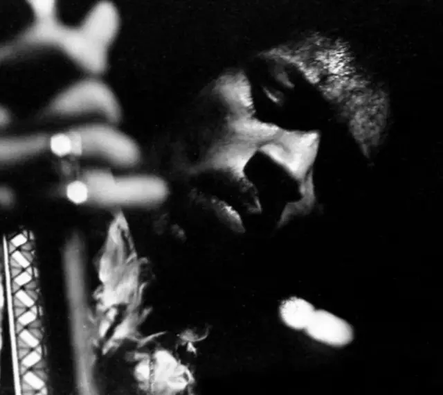 Gros plan en noir et blanc de Jimi Hendrix jouant de la guitare, évoquant l'esprit de ses albums légendaires.