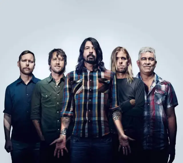 Les cinq membres du groupe Foo Fighters posent ensemble, prêts à faire vibrer le public avec leur musique.
