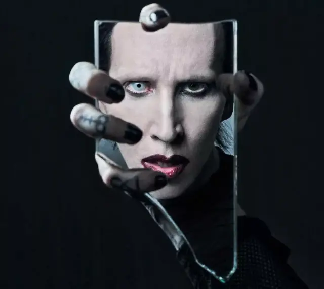 Marilyn Manson, visage décomposé dans un miroir brisé, évoquant l'esthétique sombre de ses albums.