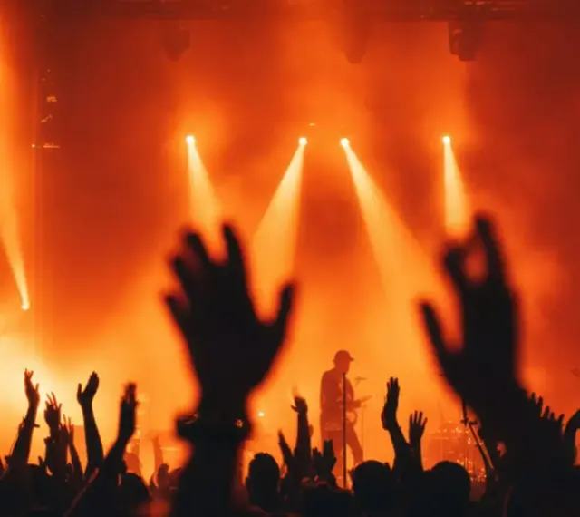 Foule en délire sous des projecteurs orangés. Le son assourdissant d'un concert peut parfois causer ce qu'est un acouphène.