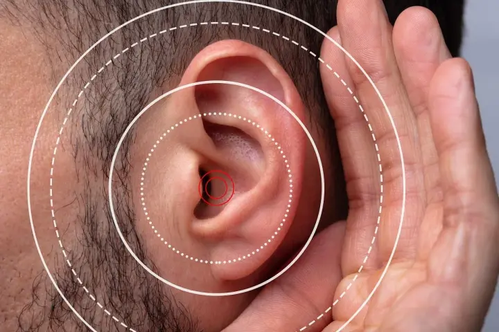 Gros plan sur une oreille humaine avec des cercles concentriques symbolisant le son. Une main est placée près de l'oreille, suggérant une gêne ou une irritation oreille boule quies.