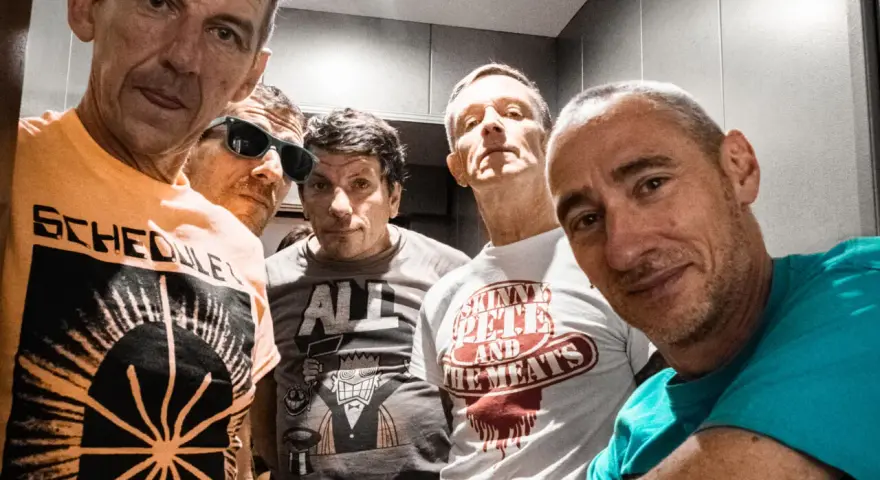 Cinq hommes aux têtes brûlantes, certains souriants, d'autres plus intenses, posent pour un selfie. Leurs t-shirts affichent des graphismes variés.