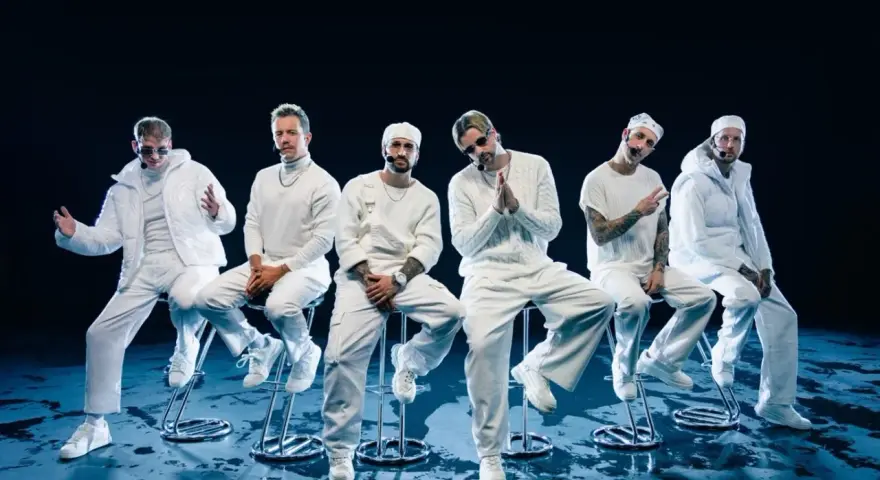 Six hommes en tenue blanche, assis sur des tabourets, évoquant l'univers des albums de Electric Callboy.