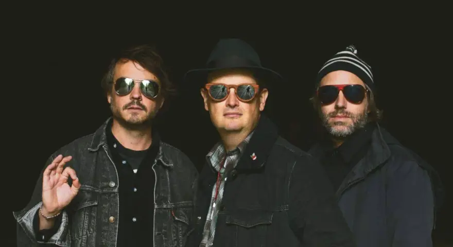 Trois hommes, lunettes de soleil, chapeau, bonnet. Ils ont l'air cool, pas comme des zombies.
