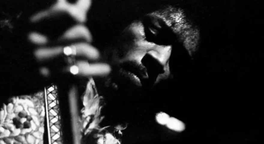 Gros plan en noir et blanc de Jimi Hendrix jouant de la guitare, évoquant l'esprit de ses albums légendaires.