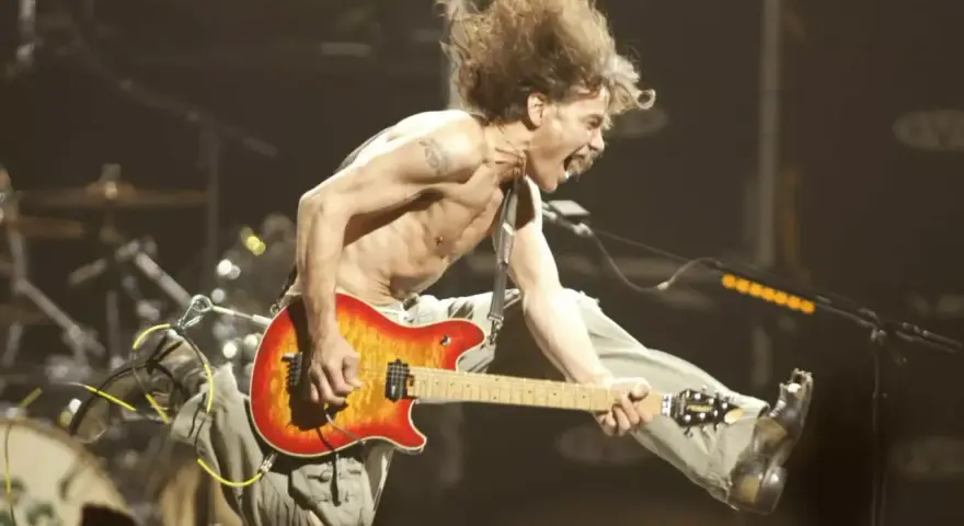 Un guitariste en plein saut, cheveux au vent, déchaîne sa guitare. Un vrai héros de la guitare en pleine action.