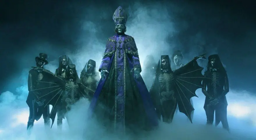 Les membres de Ghost (groupe) apparaissent dans une brume bleutée, le leader en robe violette imposante, entouré de squelettes masqués et d'une silhouette à chapeau.